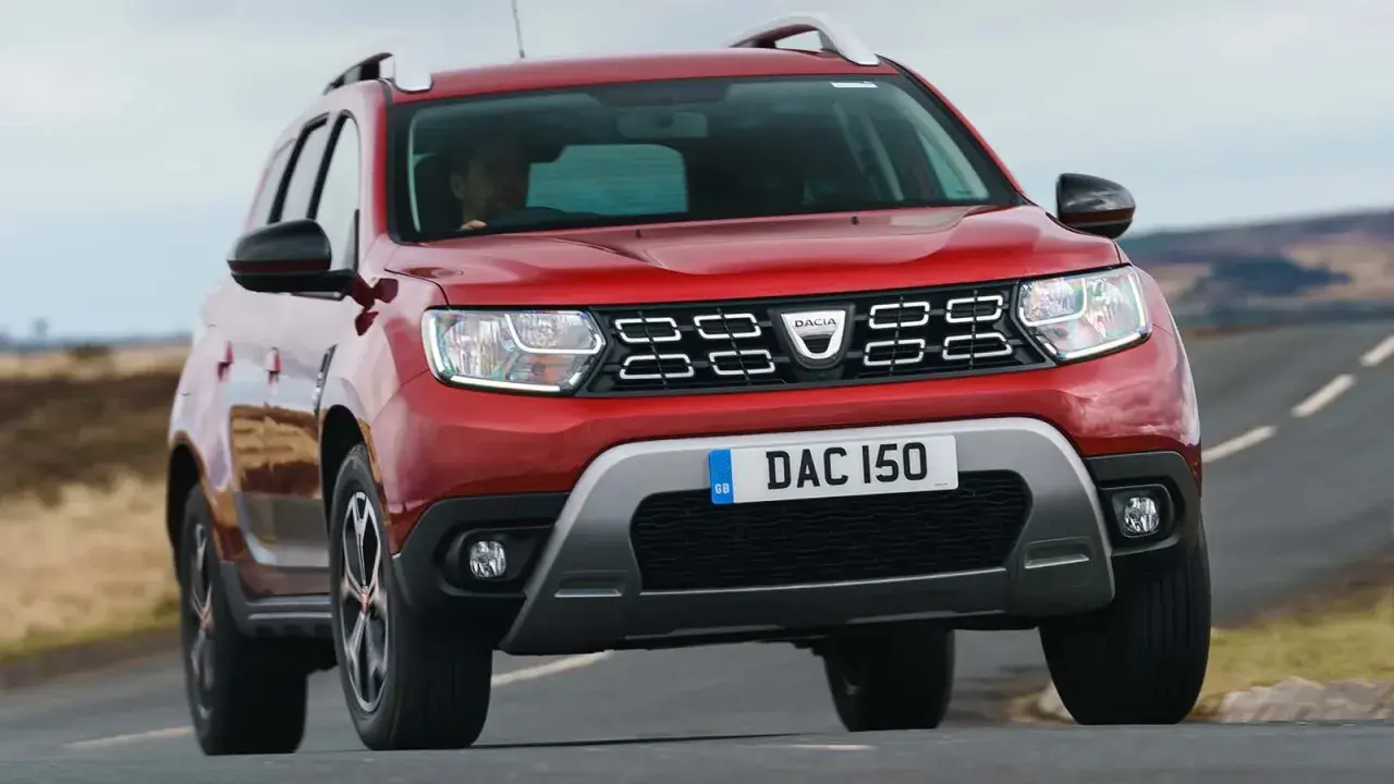 Röd Dacia Duster begagnad kör på en landsväg.
