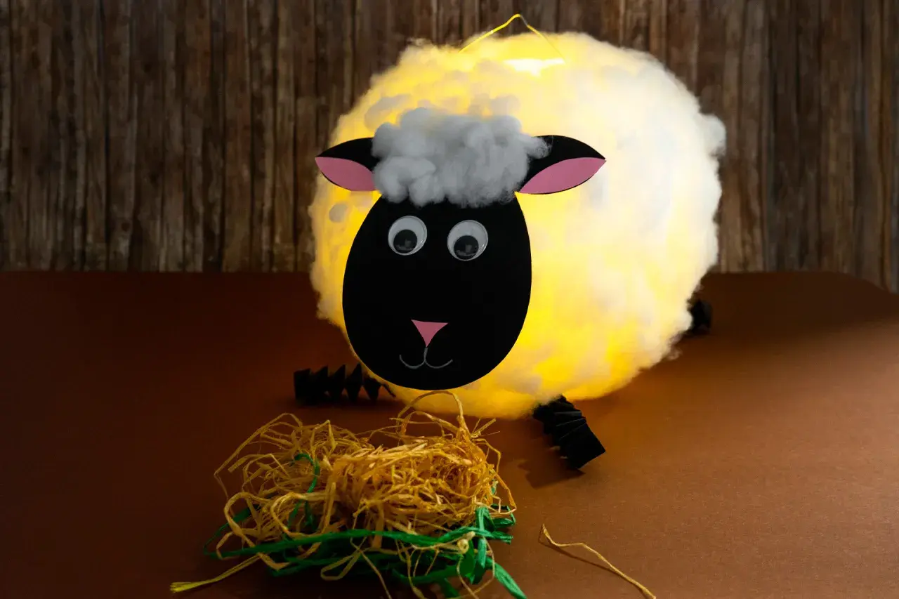 Ein leuchtendes Schaf, gebastelt aus einem Luftballon, mit Watte als Wolle und Papier für Kopf und Ohren.