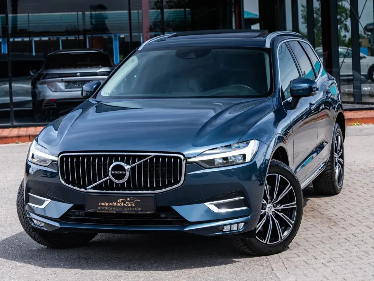 Elegancki, ciemnoniebieski SUV Volvo z chromowanym grillem. Idealny wybór dla szukających auta do 60 tys.