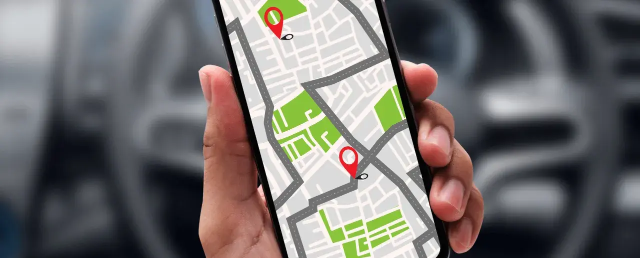 Dłoń trzyma smartfon z mapą i pinezkami. Dowiedz się, jak namierzyć telefon po numerze, by zawsze wiedzieć, gdzie jest bliska osoba.