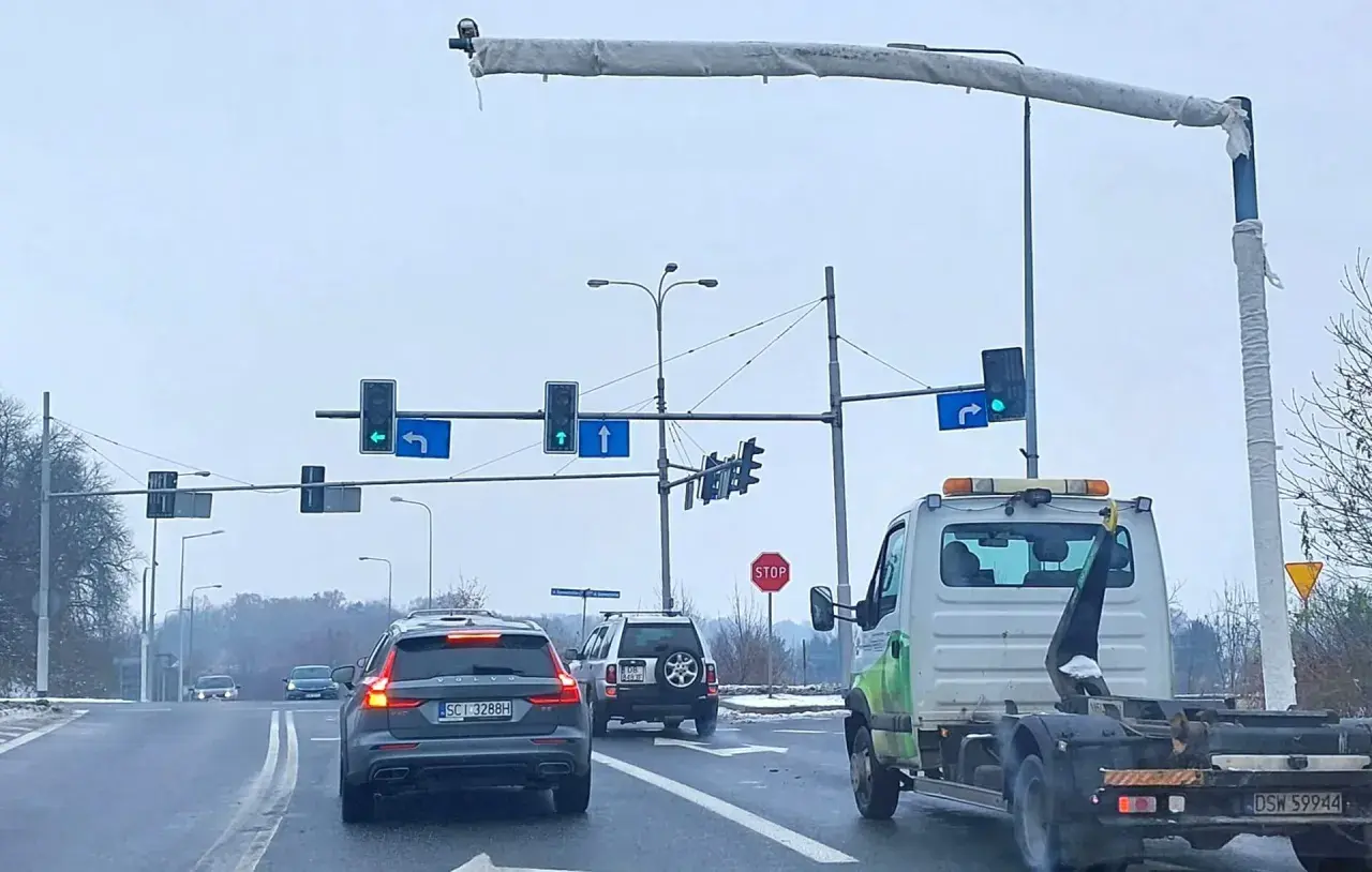 Na skrzyżowaniu widać różne rodzaje kamer monitorujących ruch. Samochody czekają na zielone światło.