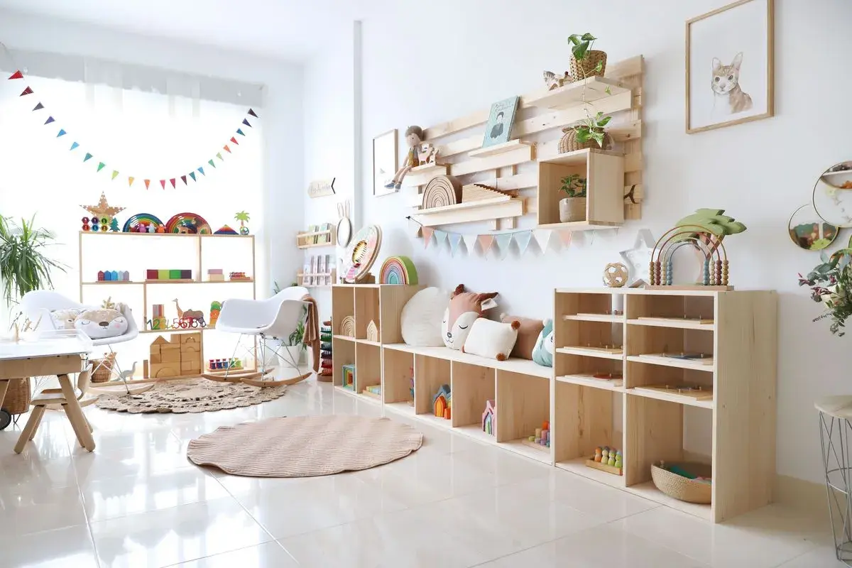 Acogedor rincón de juegos en el salón, con estanterías de madera llenas de juguetes educativos, cojines y una alfombra circular.