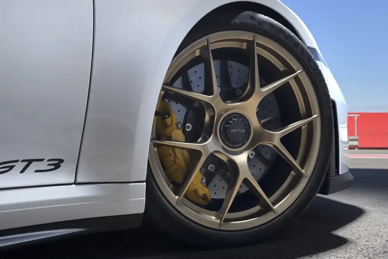 Porsche GT3 mit goldenen Felgen und gelben Bremssätteln. Die Keramik Bremsen Kosten sind hoch, aber die Leistung ist unschlagbar.