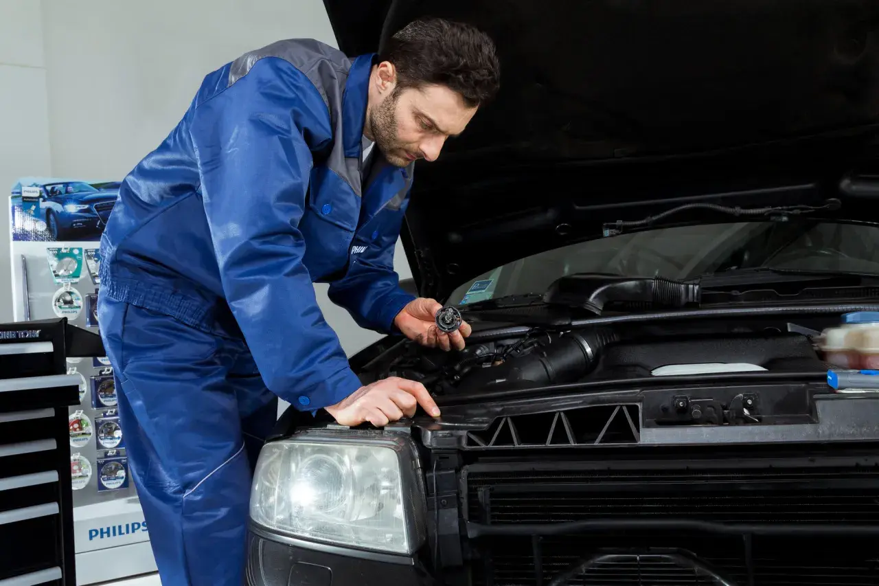 Mechanik wymienia żarówkę w Nissan Qashqai J10. Wymiana żarówki przód wymaga precyzji.