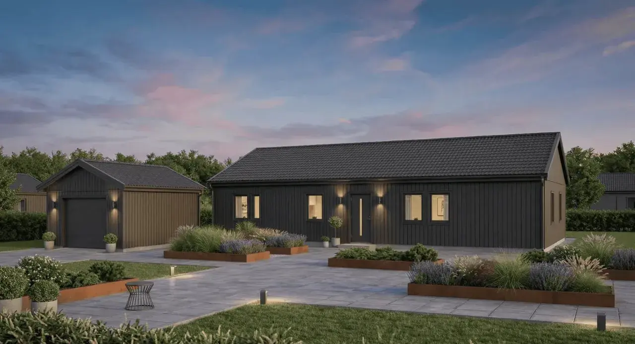 Modern dark gray house and detached garage with landscaped garden beds and paved driveway at dusk.