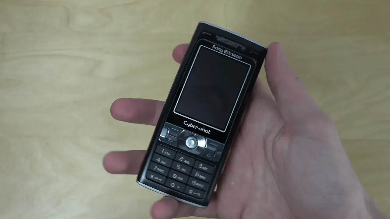Dłoń trzyma czarny telefon Sony Ericsson k800i z napisem Cyber-shot.