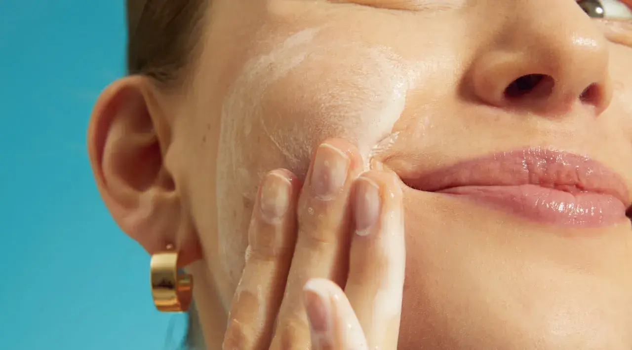 Mani delicate massaggiano schiuma sul viso, cercando sollievo per la pelle irritata.