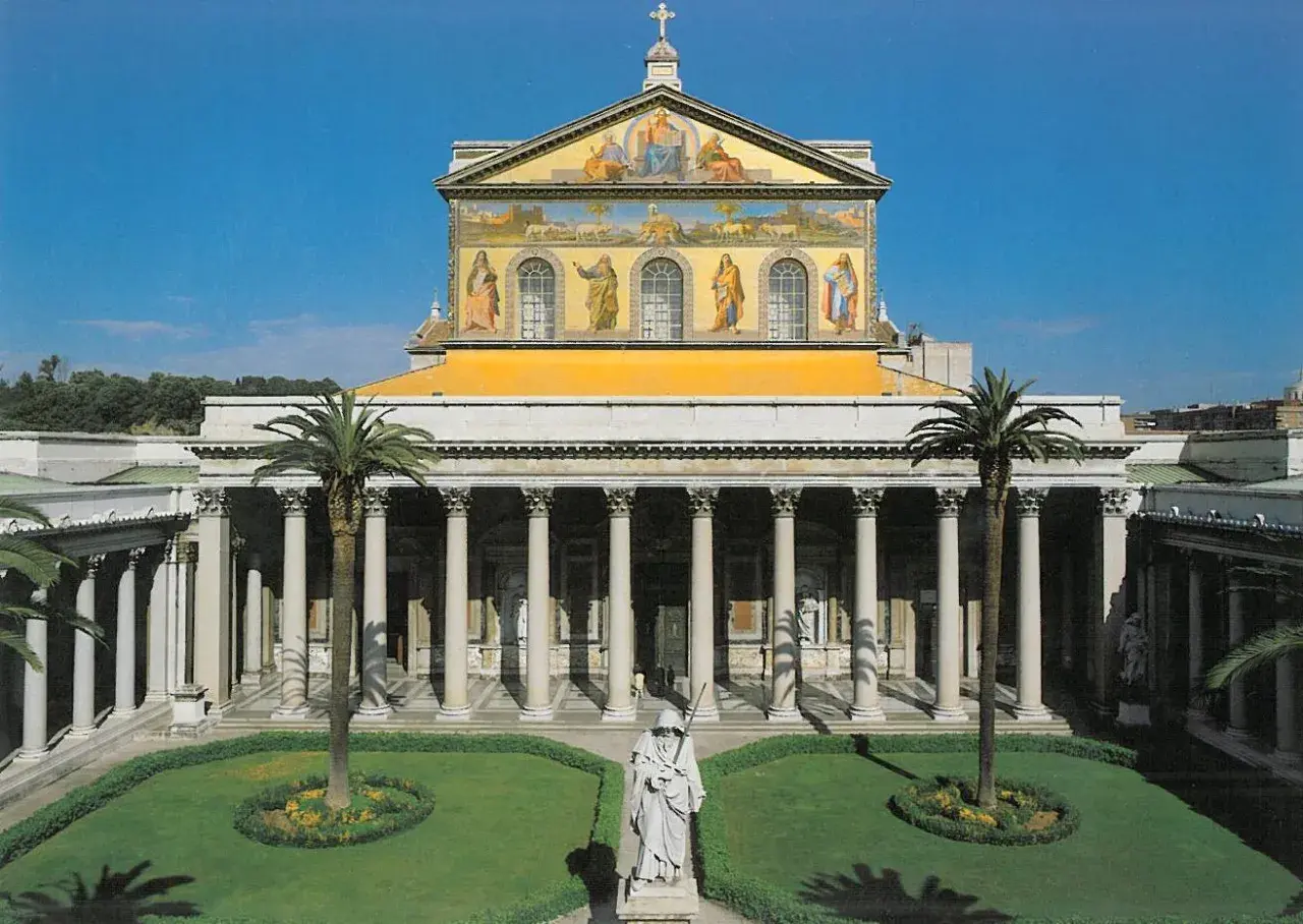 La **cattedrale San Paolo Roma** vista dal cortile con statue, palme e un prato curato.