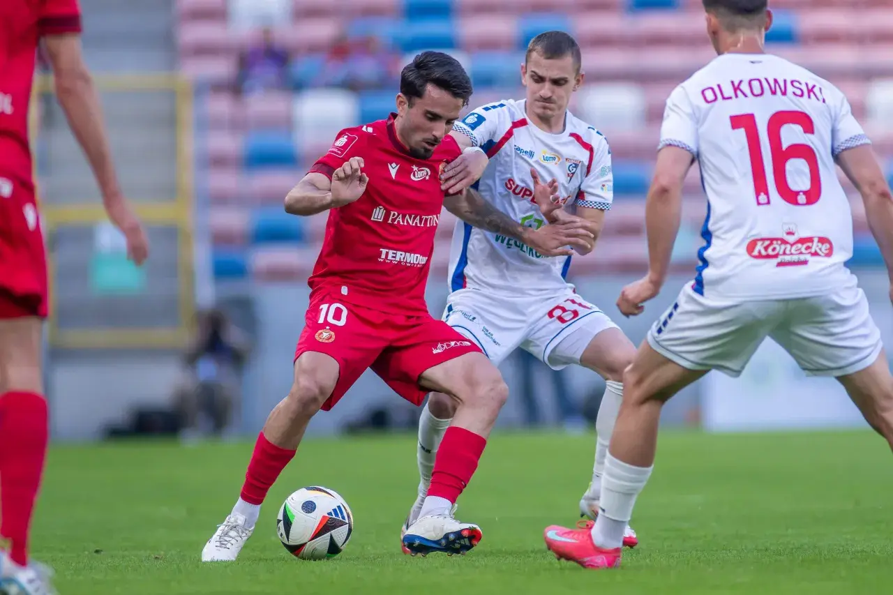 Piłkarze Widzewa Łódź i Górnika Zabrze walczą o piłkę. Czerwona koszulka z numerem 10 i biała z numerem 16.