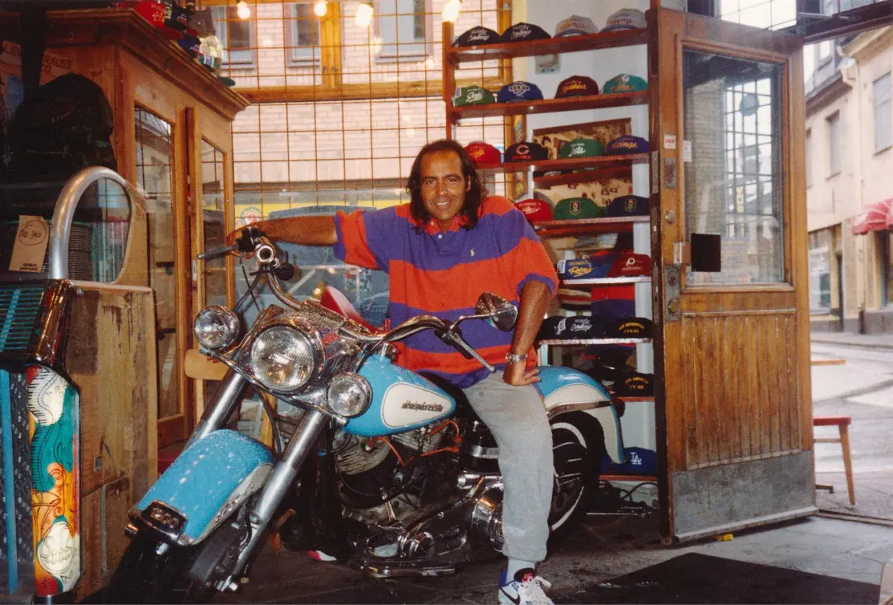 Man på motorcykel i en butik med kepsar, kanske en del av "Broadway & Sons" sortiment.