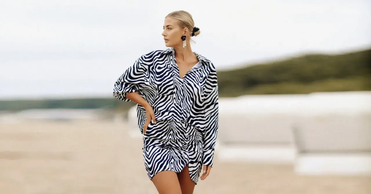 Kobieta o figurze klepsydry plus size w sukience w panterkę na plaży.