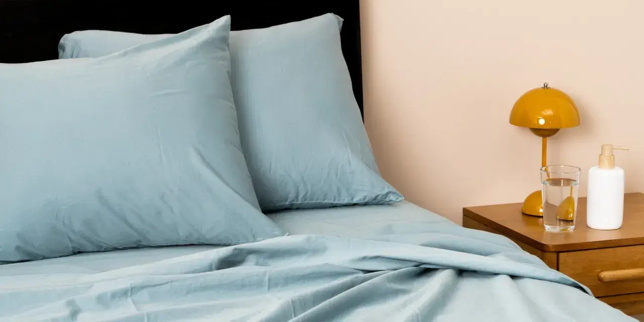 Soft, light blue sheets and pillows create a cozy bed. This material looks like the best material for sheets, promising comfort and style.