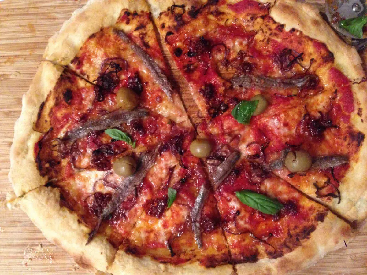 Pizza napolitana con anchoas, aceitunas y albahaca. Una delicia para disfrutar en cualquier momento.