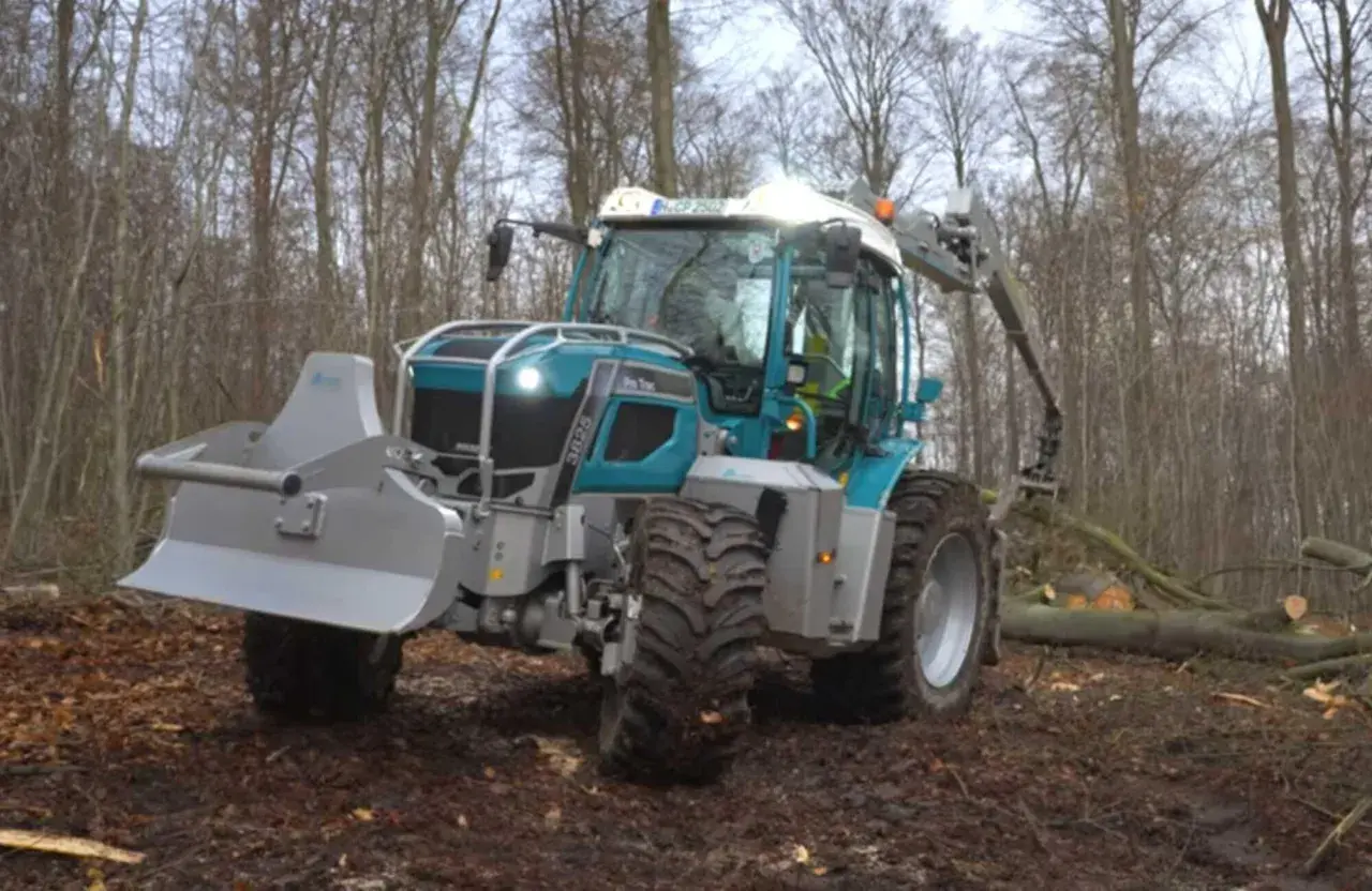 Ein moderner **Traktor mit Kran** im Wald, bereit für die Holzernte.