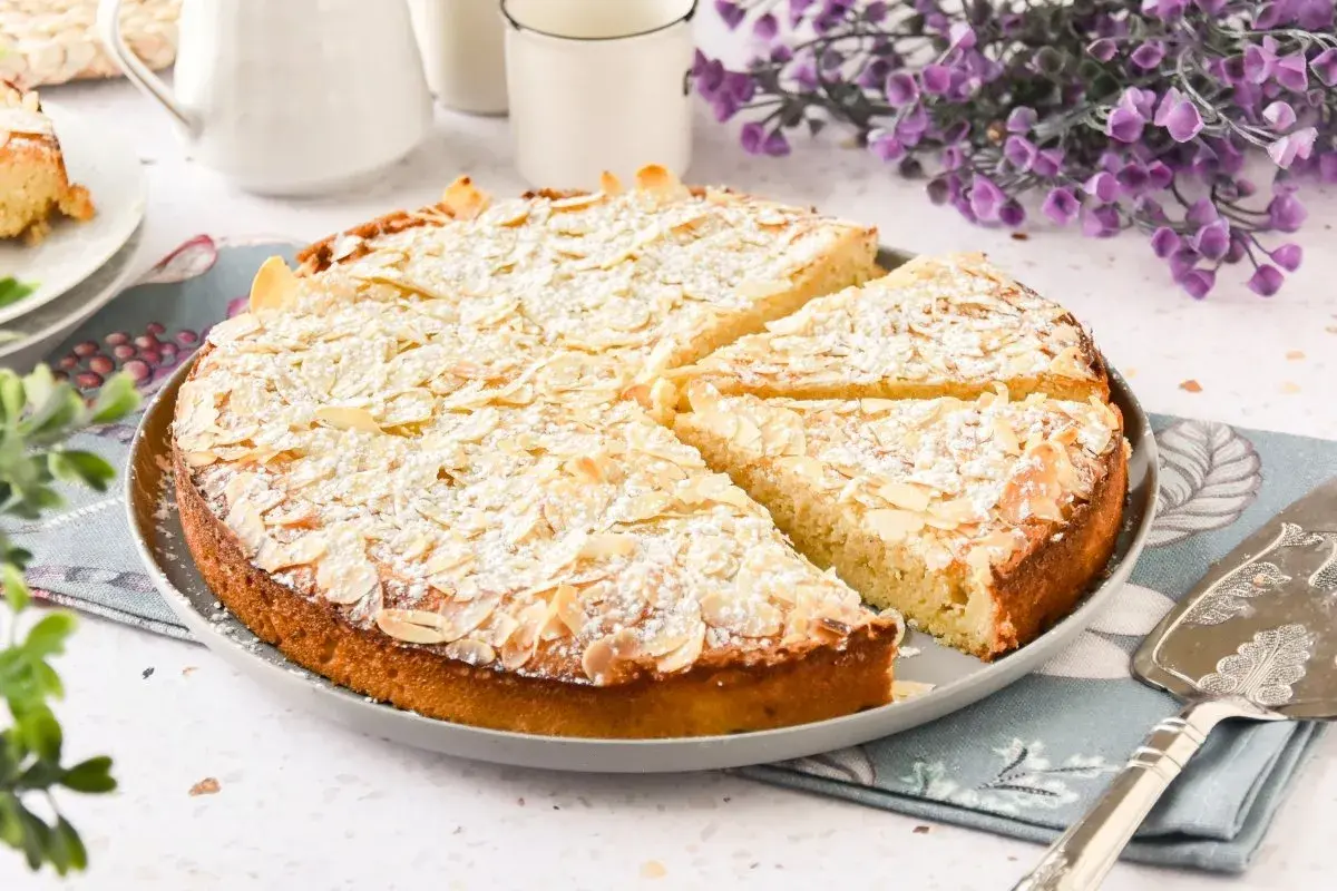 Tarta de almendras, espolvoreada con azúcar glas y almendras laminadas, lista para ser servida.