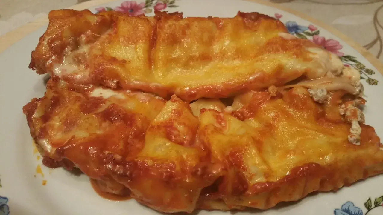 Cannelloni ricotta e carne gratinati al forno, con sugo rosso e formaggio filante.