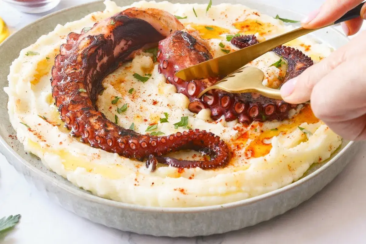 Un delicioso pulpo a la brasa, con sus tentáculos crujientes, servido sobre un puré cremoso.
