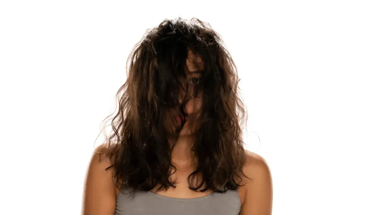 Frau mit dunklem, welligem Haar, das ihr Gesicht verdeckt. Ein Blick auf ihre Schultern und den Ansatz ihres Halses. Vielleicht ist dies das Ergebnis einer neuen locken routine.