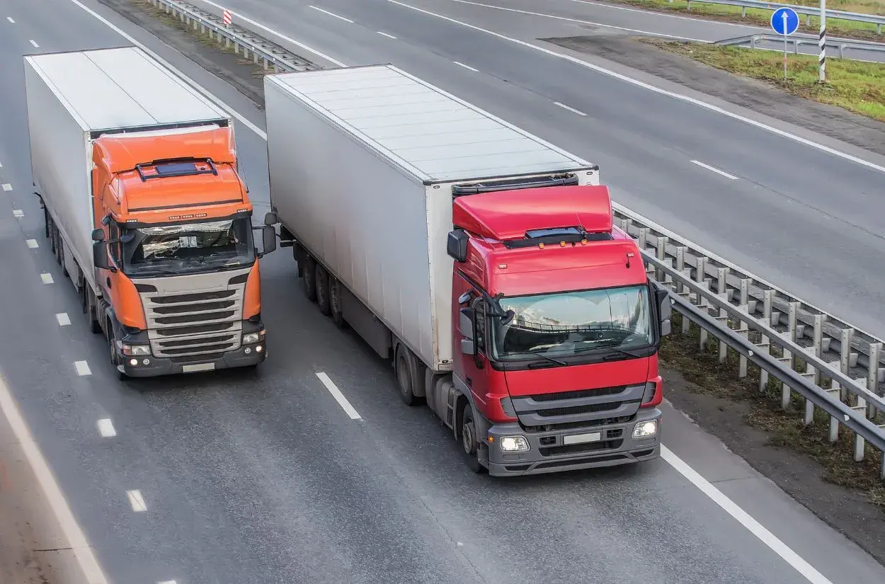 Dwa ciężkie samochody ciężarowe jadące autostradą, przestrzegając dopuszczalny nacisk na oś w Polsce.