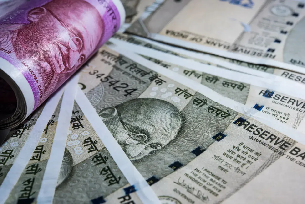 Stos banknotów, w tym fioletowy 2000 rupii i szare 500 rupii, z wizerunkiem Mahatmy Gandhiego. Waluta Indii.