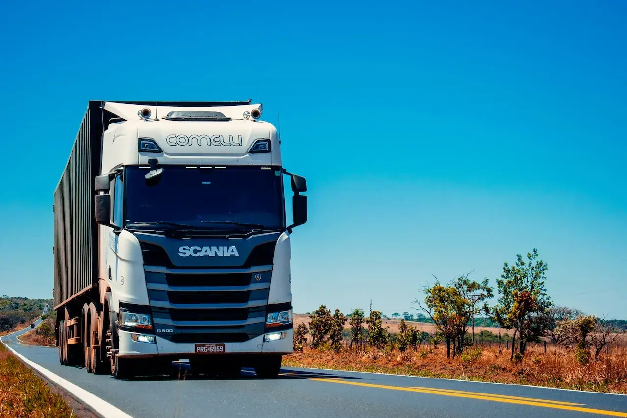 Biała Scania z naczepą jedzie po pustej drodze. Zastanawiasz się, ile ton można załadować na tira?