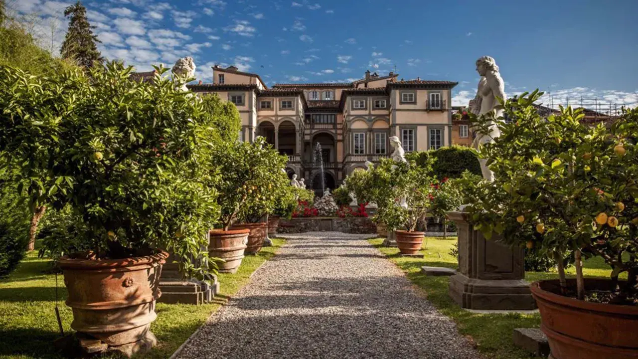 Palazzo Pfanner et son jardin à Lucca, avec des arbres en pot, des statues et une fontaine.