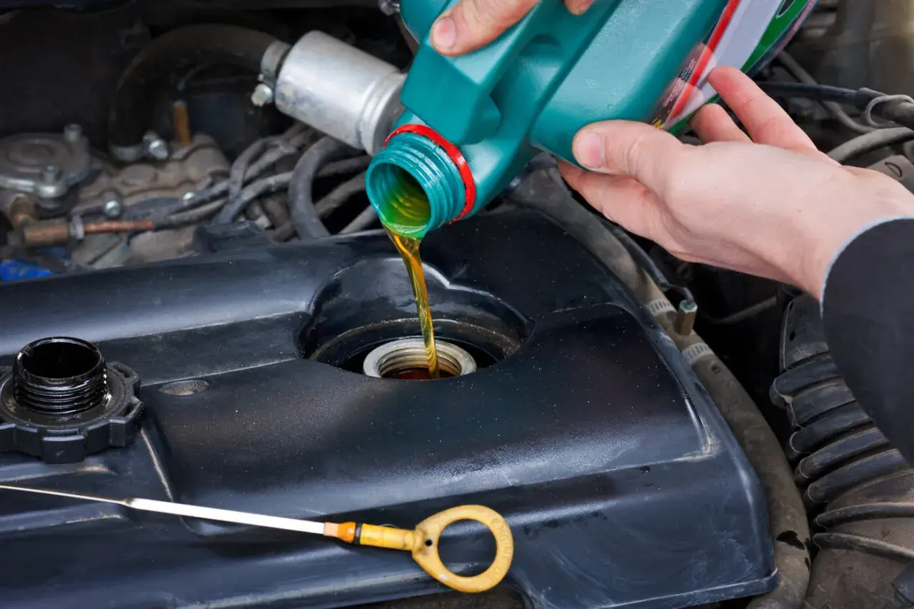 Persona vertiendo aceite nuevo en el motor de un coche. Es un mantenimiento esencial para rellenar aceite coche.