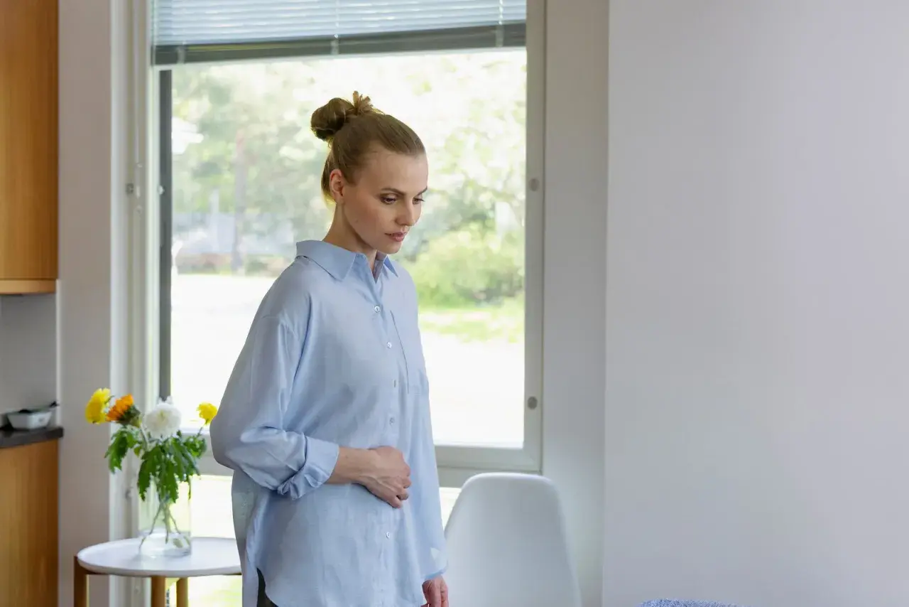 Kvinna med handen på magen, kanske oroande över klamydia symtom.