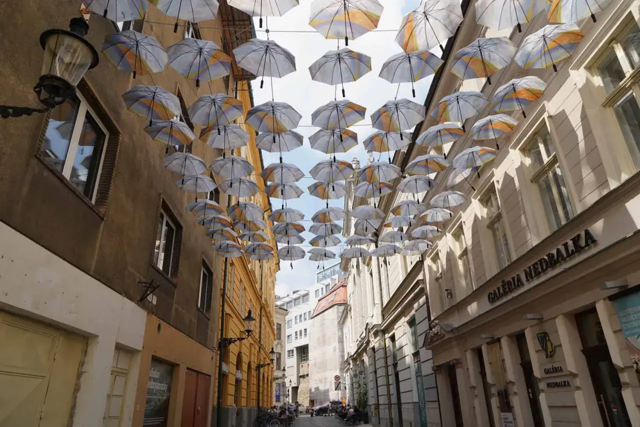 Bratislava: Hängende Regenschirme über einer Gasse mit Geschäften. Ein toller Anblick bei den vielen Dingen, die man in Bratislava unternehmen kann.