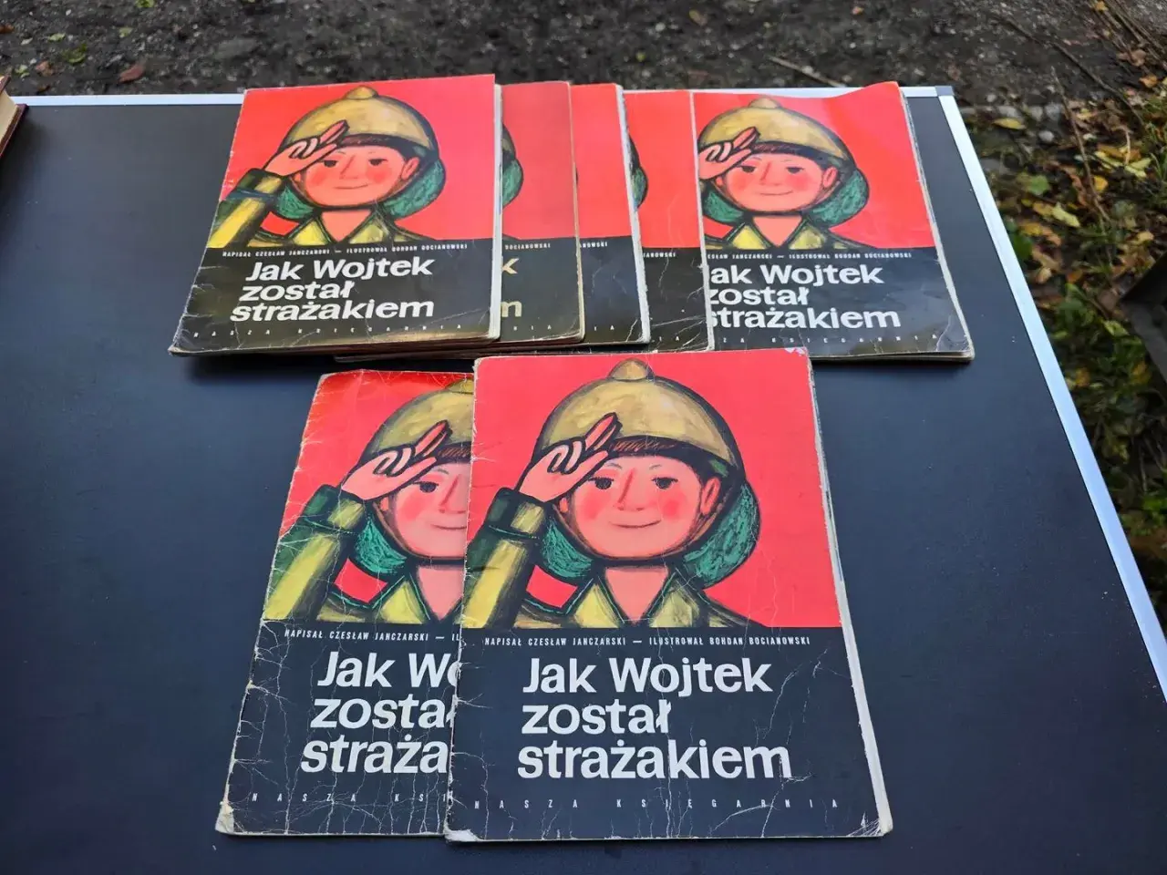 Okładki książek z ilustracją chłopca w hełmie i napisem "Jak Wojtek został strażakiem".