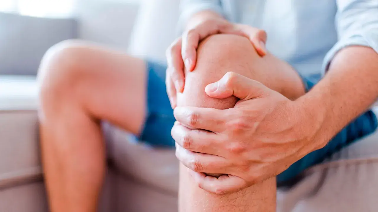 Mann hält sein Knie, das einen stechenden Schmerz im Knie anzeigt.