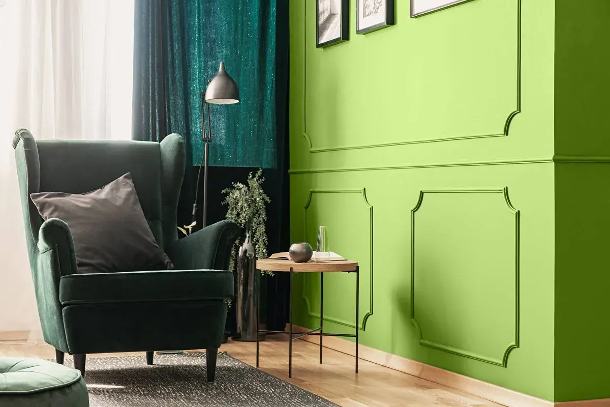 Zielona, aksamitna sofa i zasłony tworzą przytulną atmosferę. Kolor oliwkowy z jakim kolorem pasuje? Zobacz, jak świetnie komponuje się z jaskrawą zielenią ścian.