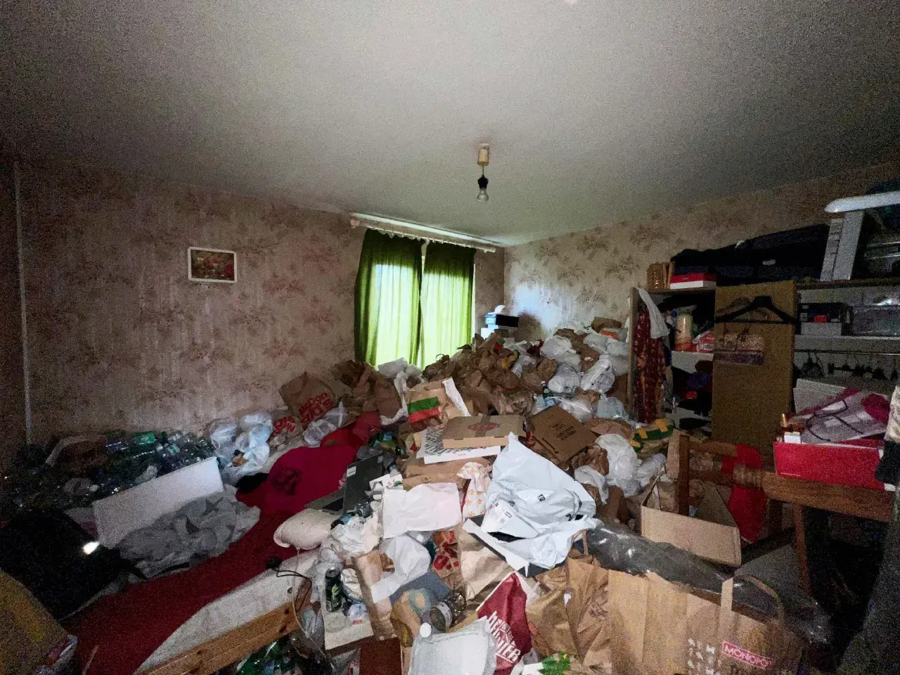 Un logement insalubre envahi par des montagnes de sacs et de détritus. La pièce est encombrée, rendant la circulation difficile.
