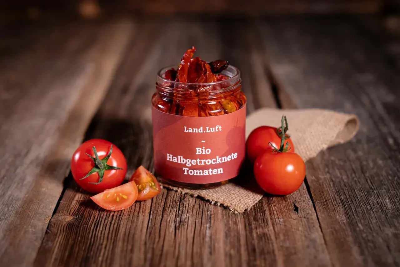 Glas mit halbgetrockneten Tomaten, frische Tomaten und Scheiben auf Holzhintergrund.