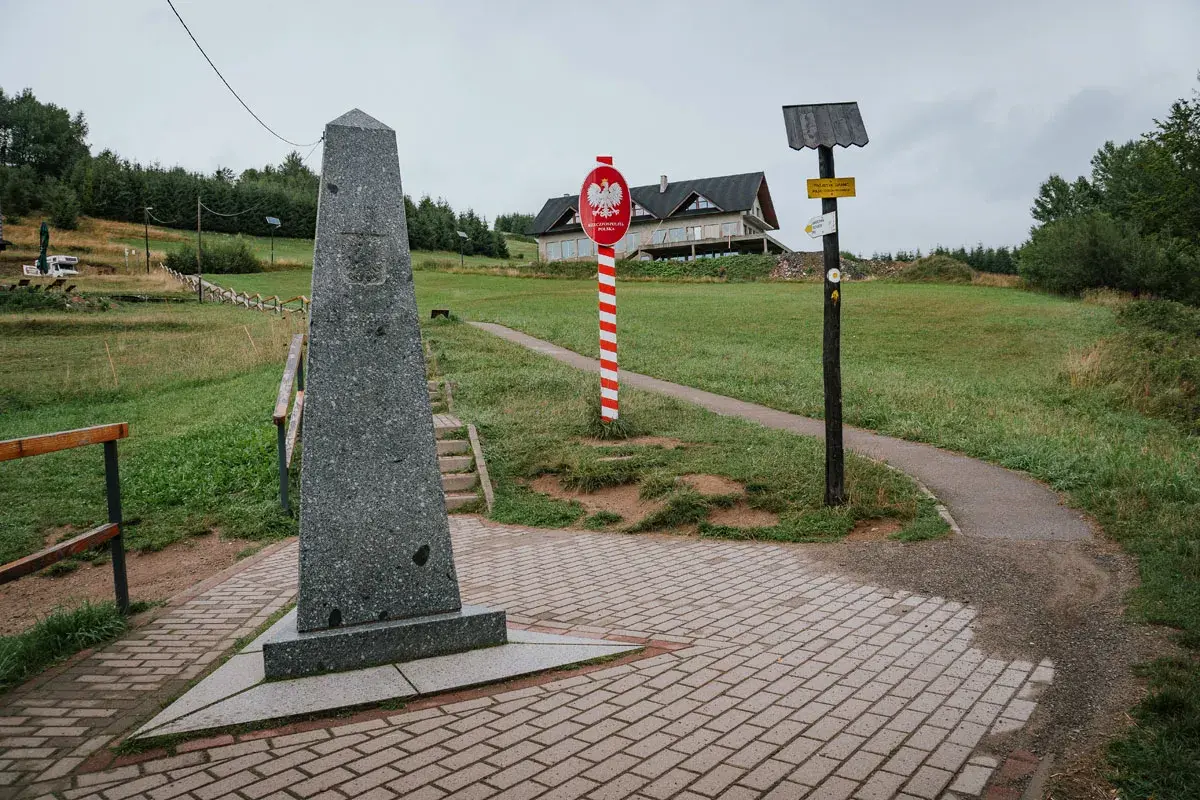 Pomnik na trójstyku Jaworzynka. Znaki graniczne i drogowskazy wskazują trasę.