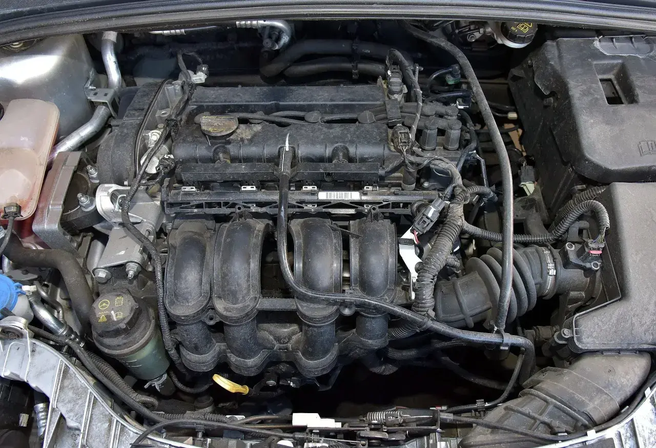 Silnik Ford Focus MK3 1.6 benzyna, widok z góry. Widać kolektor dolotowy, cewki zapłonowe i inne elementy.