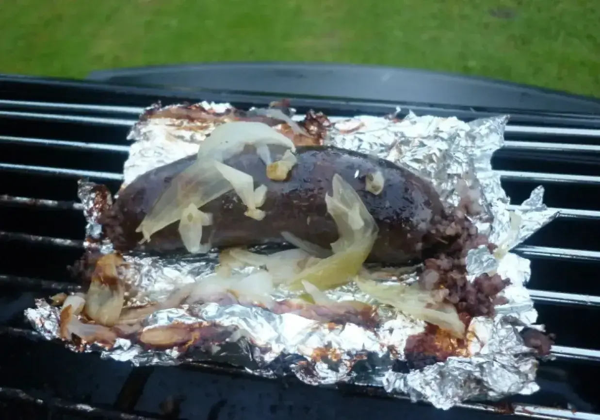 Kaszanka z grilla, soczysta i aromatyczna, pieczona na folii aluminiowej z cebulką. Idealna na letnie wieczory.