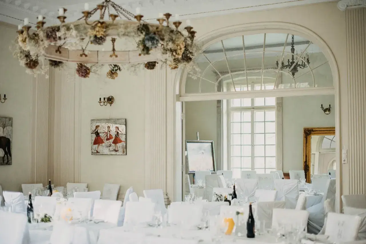 Elegancka sala bankietowa w pałacu Grąbkowo, udekorowana kwiatami i przygotowana na przyjęcie.