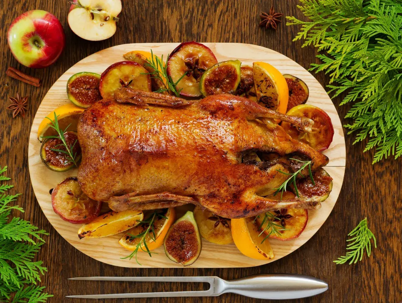 Pieczona kaczka w pomarańczach, jabłkach i figach, ozdobiona rozmarynem. Aromatyczne danie świąteczne.