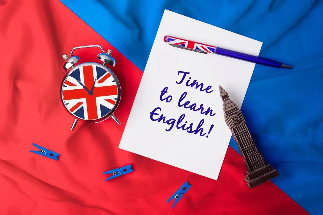Budzik z flagą Wielkiej Brytanii, długopis i napis "Time to learn English!" na tle brytyjskich barw. Sebastian, czas na naukę!