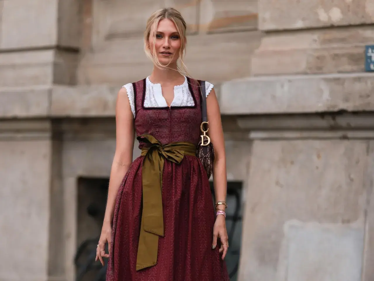 Frau mit Dirndl und einer grünen Schürze, die sie elegant um die Taille gebunden hat.