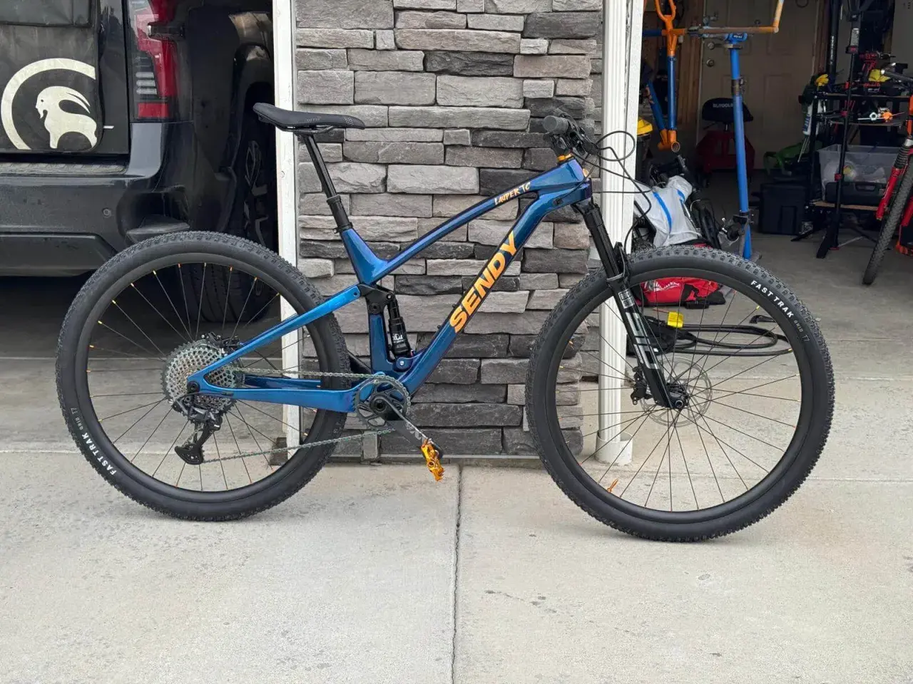 A blue Sendy mountain bike with full suspension, ready for any trail. Its robust mountain bike suspension system promises a smooth ride.