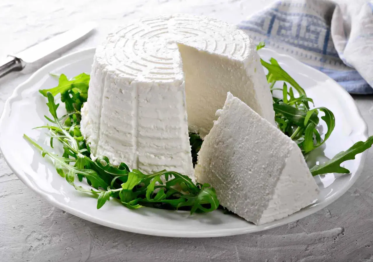 Formaggio fresco su un piatto bianco con rucola, ideale per chi cerca alimenti senza caseina.