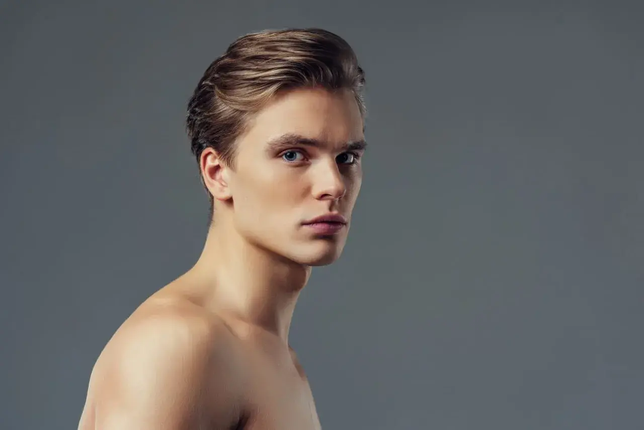 Joven con pelo liso hombre, ojos azules y piel clara, mirando a la cámara con expresión seria.