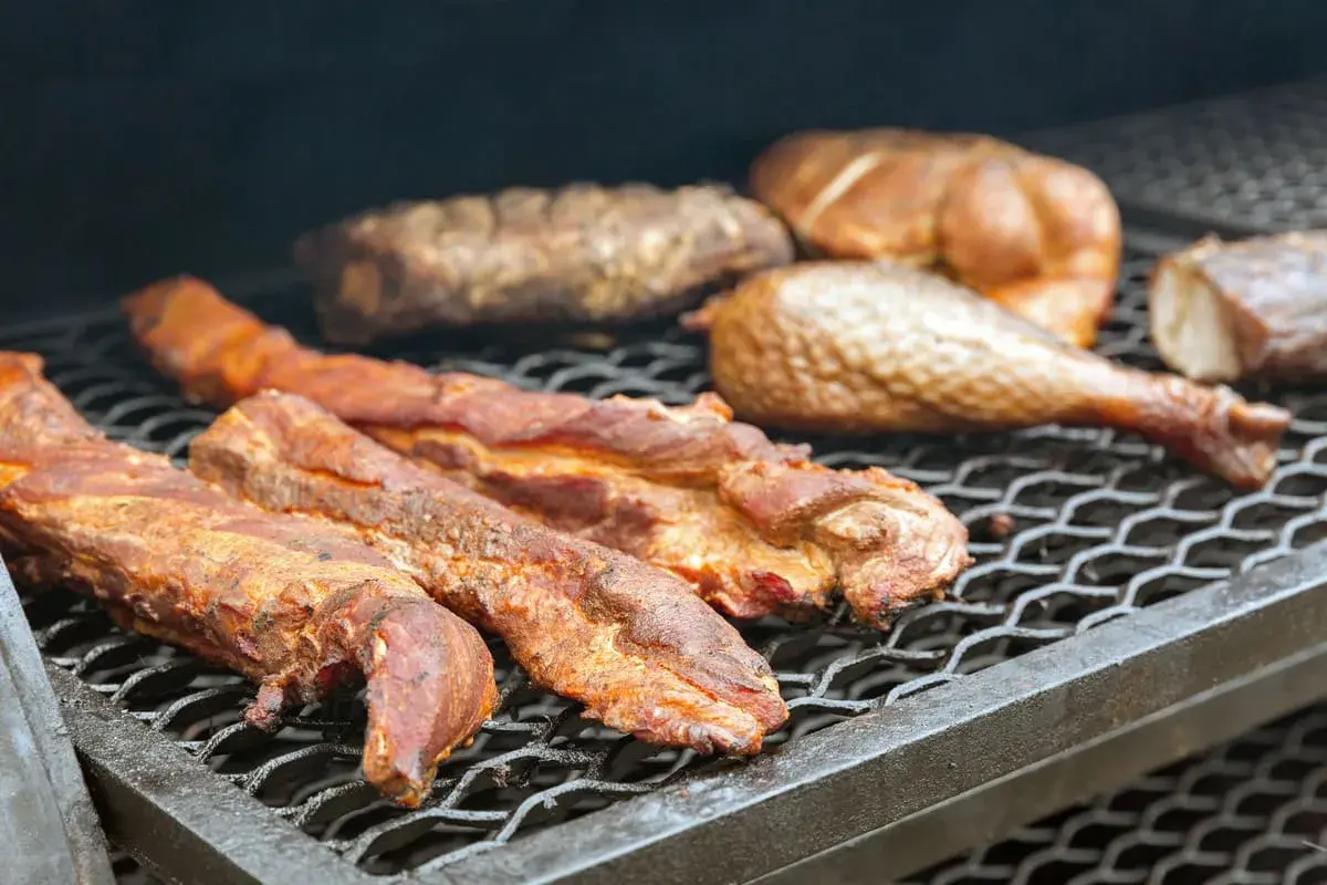 Plusieurs morceaux de filet de porc fumé, dorés et juteux, reposent sur une grille de barbecue, prêts à être dégustés.