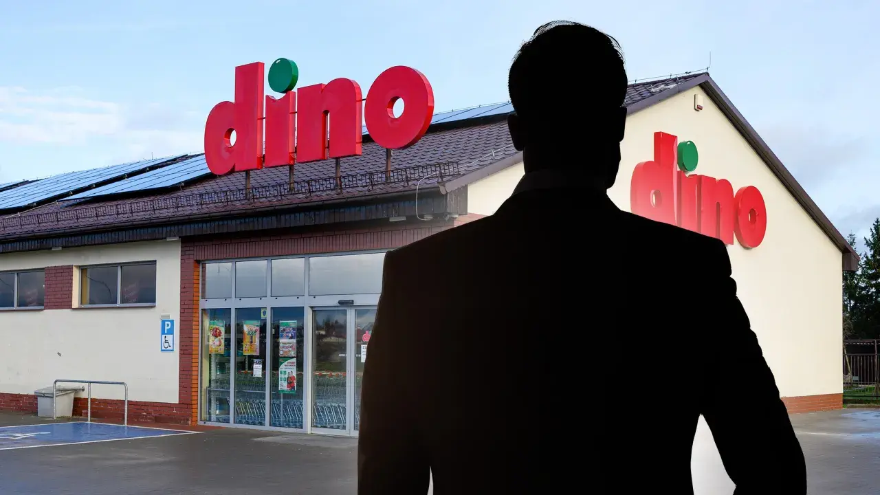 Sylwetka mężczyzny w garniturze na tle sklepu Dino.