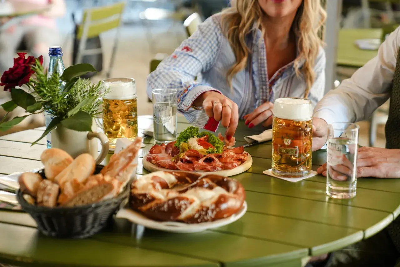 Un tavolo al birrificio Forst Lagundo con birra, salumi, pane e un pretzel.