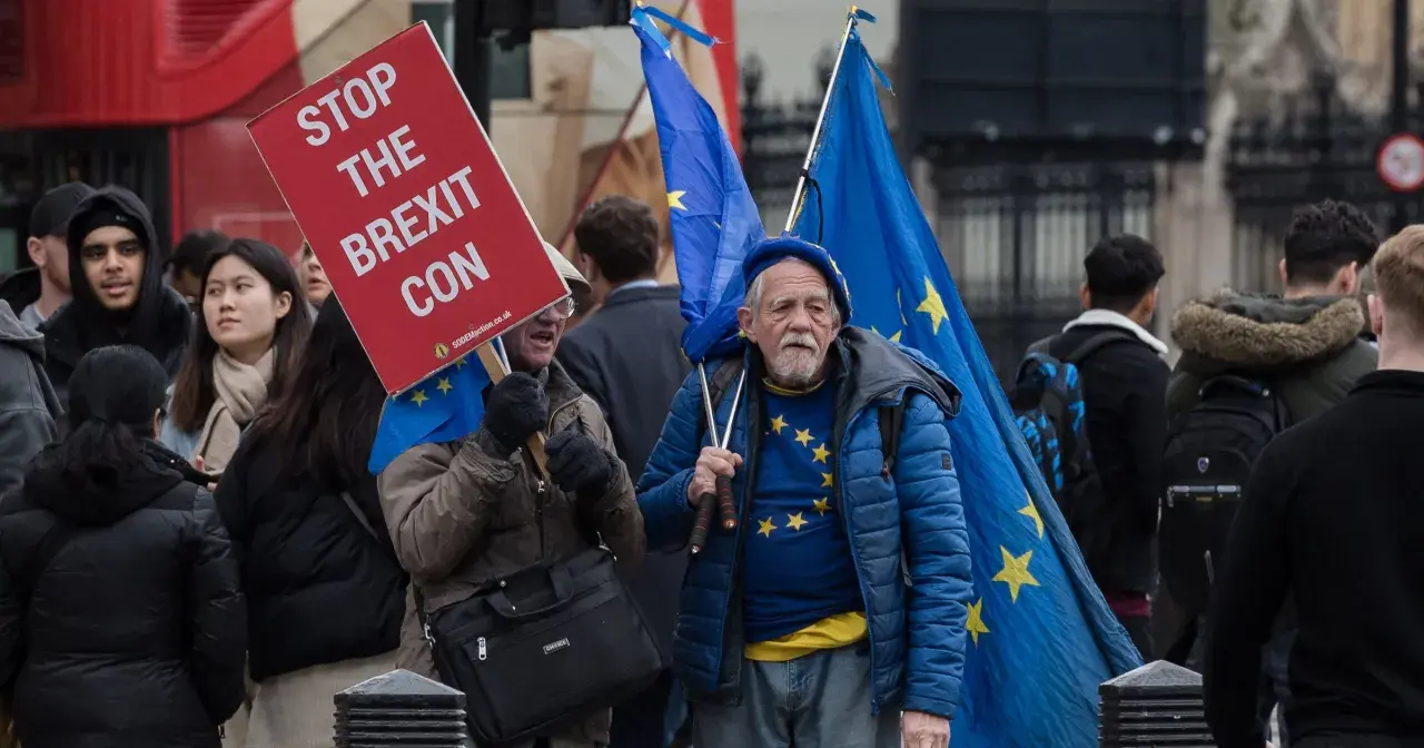 Protestujący w Wielkiej Brytanii z flagami UE i transparentem "Stop the Brexit Con".