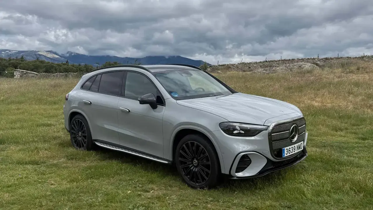 Un SUV gris moderno, con tracción 4 matic, descansa en un campo verde con montañas nubladas al fondo.