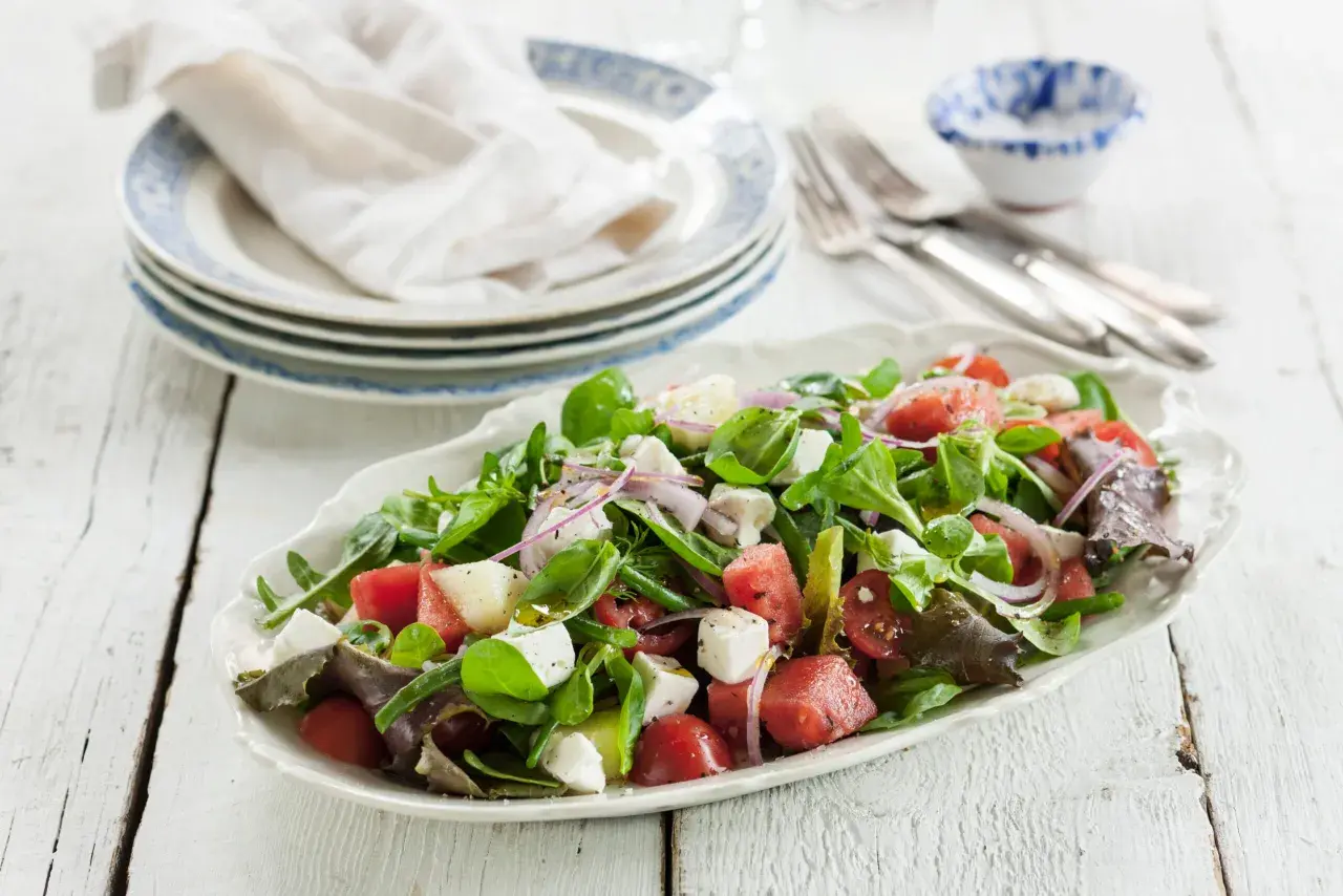 En fräsch sallad med vattenmelon, fetaost, tomater och gröna blad. Perfekt för en varm sommardag, den godaste melonsalladen!
